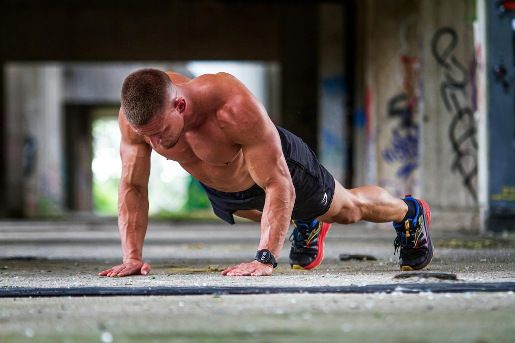 Shirtless caucasian man doing push-ups in an urban setting, showcasing strength and fitness.