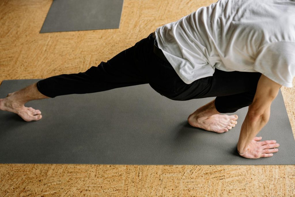 A man performing a crescent lunge pose on a yoga mat indoors, emphasizing balance and fitness.